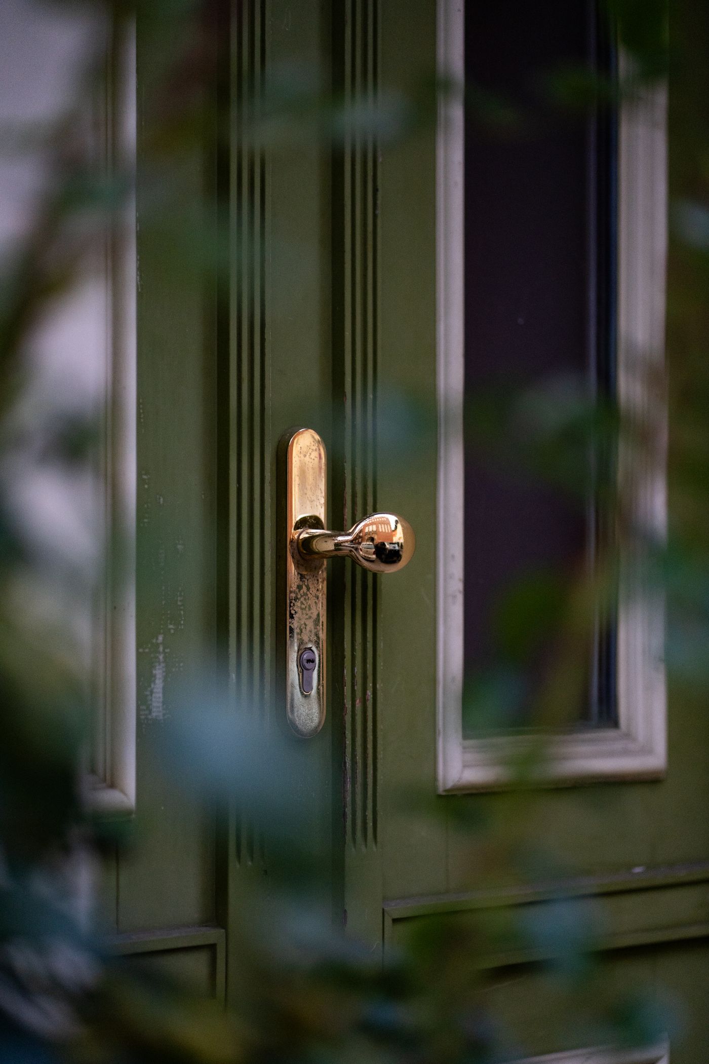A freshly painted green front door with polished brass hardware