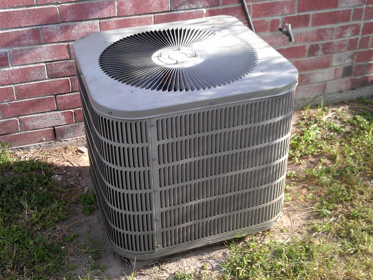 A clean residential outdoor air conditioning condenser unit beside a home