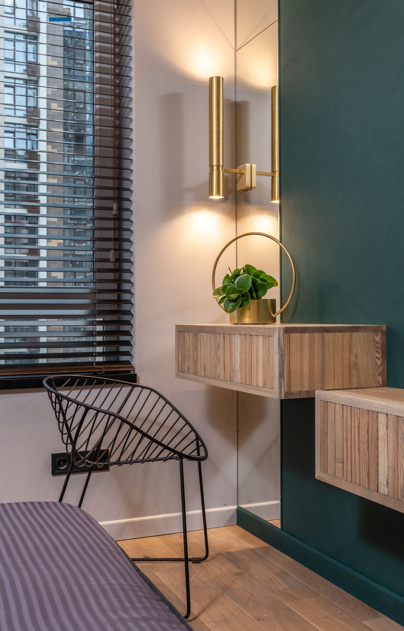 Interior corner with window blinds, a wall-mounted shelf, and a brass light fixture