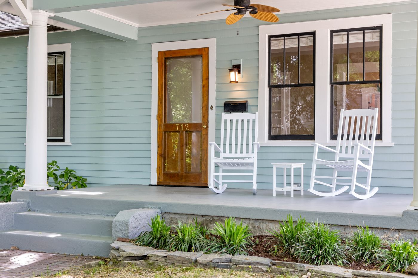 A tidy front porch with rocking chairs on a well-kept home exterior
